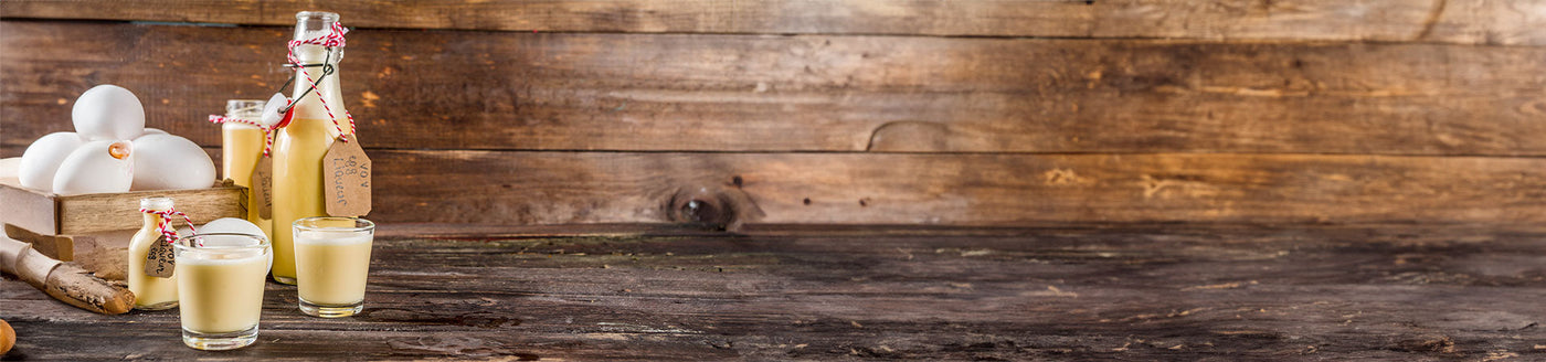 Gläser und eine Flasche mit Eierlikör neben einem Eierkorb