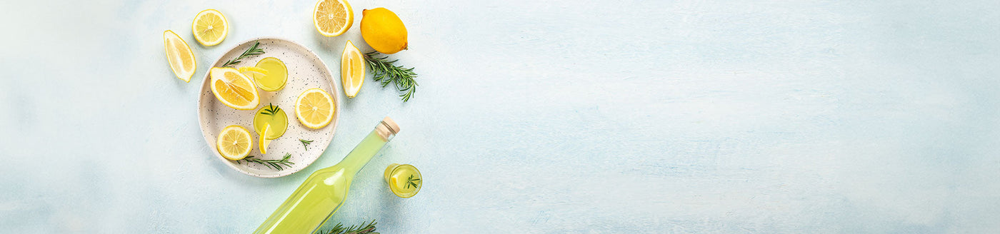 Liegende Flasche mit Limoncello neben einem Teller mit Zitronen