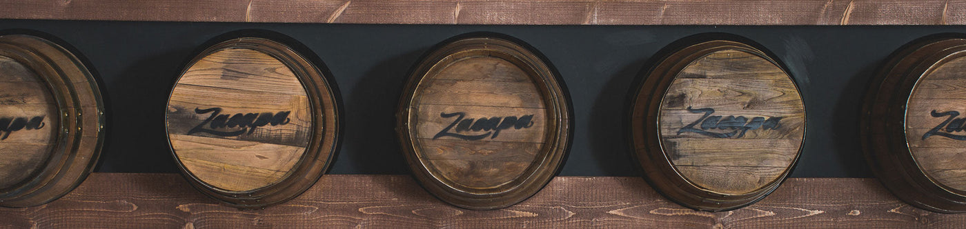 Rum reift in Holzfässern mit Ron Zacapa Logo an einer dunklen Wand in edler Holzverkleidung