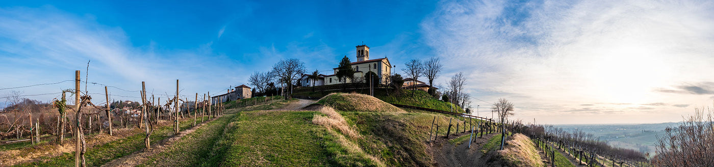 Weinberge in Friaul-Julisch Venetien mit Hügeln und Dorfkirche unter klarem Himmel