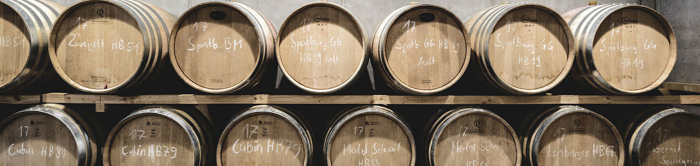 Holzfässer im Weinkeller des Weinguts Jürgen Ellwanger, bekannt für hochwertige deutsche Rot- und Weißweine