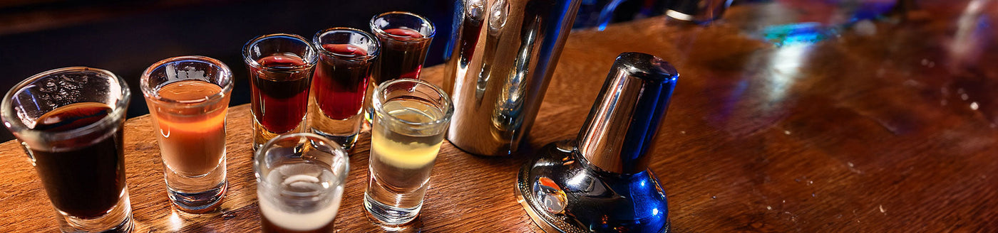 Schokolikör im Shotglas neben weiteren Shotgläsern auf einer Holztheke