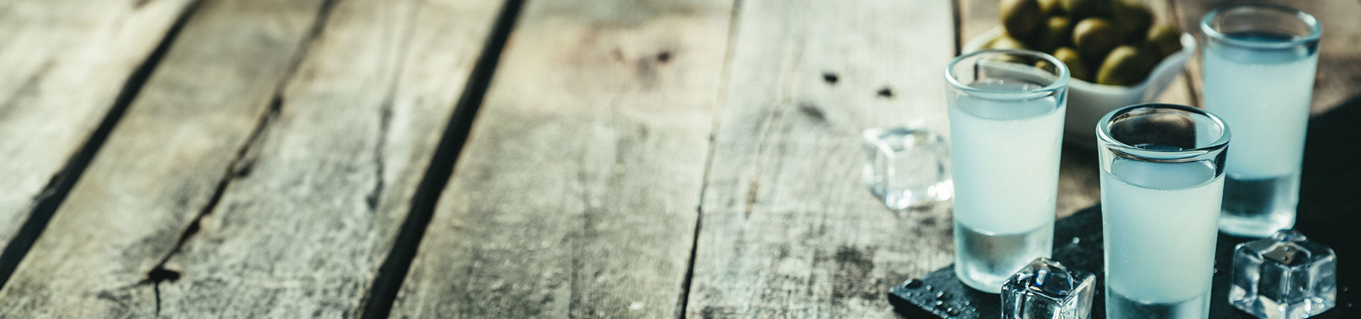 Griechischer Ouzo in gekühlten Shotgläsern auf einem Holztisch
