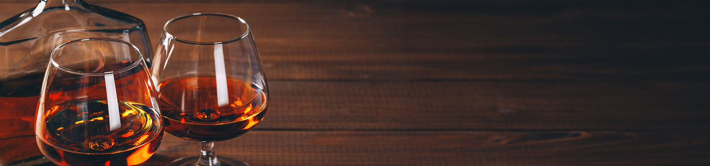 Cognac in Cognacgläsern auf einem dunklen Holztisch
