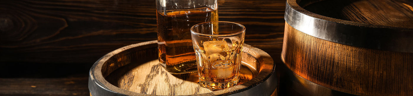 Whiskyglas und Whiskyflasche mit Scotch Whisky auf einem Holzfass