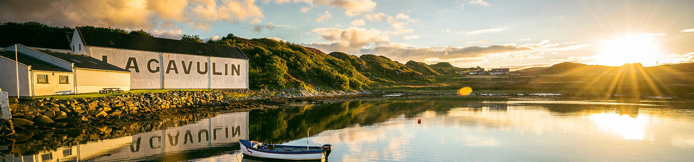 Panoramablick auf die Lagavulin Destillerie auf Islay im Sonnenlicht – Ursprung des rauchigen Single Malt Whiskys