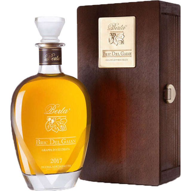 Eine 0,7-Liter-Glasflasche Grappa Berta Bric del Gaian 43% von Grappa Berta steht elegant neben einer Holzkiste mit einem goldenen Etikett.